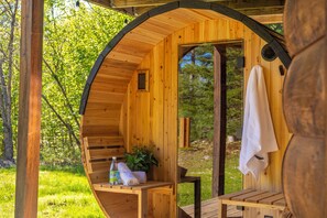 A wooden cabin with a curved exterior, a bench, a towel, and a bottle of water.