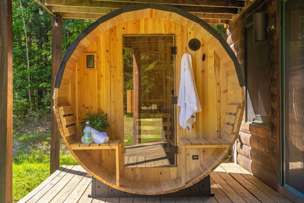 Un sauna en bois avec un banc, une serviette accrochée à la porte et une bouteille de Polar posée sur le banc.