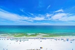 Ein Strand mit weißem Sand, blauem Himmel und türkisfarbenem Meer.