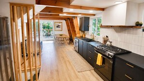 A modern kitchen with a wooden ceiling, black cabinets, and a large stove. - Modern & Cozy, Family-Friendly Cabin (Lake Arrowhead)
