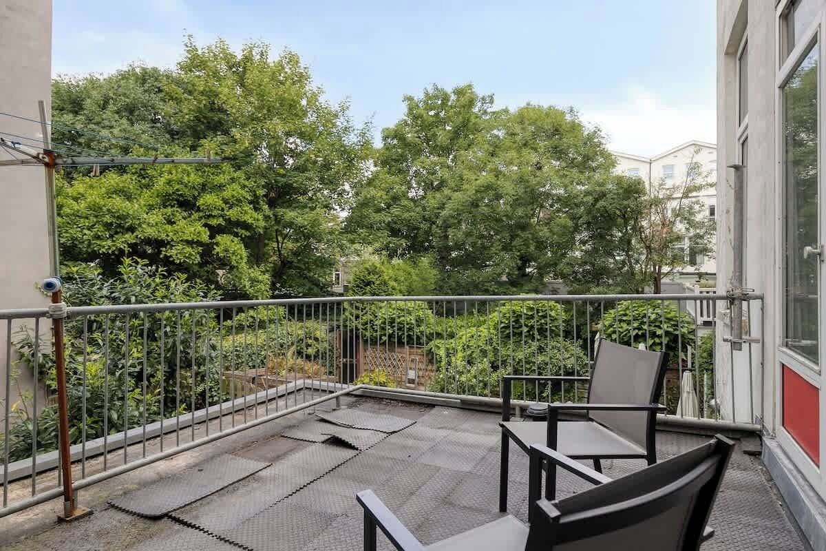 Ein Balkon mit Metallgeländer, einem Tisch und zwei Stühlen.