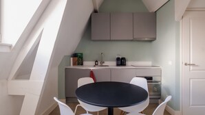 Eine moderne Küche mit Essbereich, weißen Stühlen und einem schwarzen Tisch.
