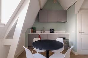 Eine moderne Küche mit Essbereich, weißen Stühlen und einem schwarzen Tisch.