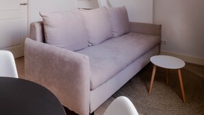 Ein modernes Schlafzimmer im Loft-Stil mit hohen Decken, freiliegenden Balken, einem hellen Sofa, einem runden Tisch und einer hängenden Leuchte.