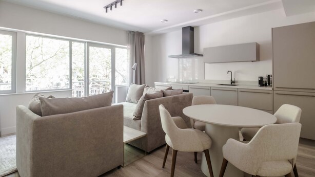 A modern living room with a sofa, chairs, and a dining table.