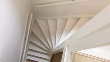 Un escalier en colimaçon blanc se trouve dans une pièce dont le sol est en bois et les murs sont blancs.