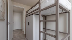 A bunk bed with a white mattress, a wooden floor, and a white wardrobe in a hallway. - Modern 3BR Apartment in Rotterdam Centre (Rotterdam)