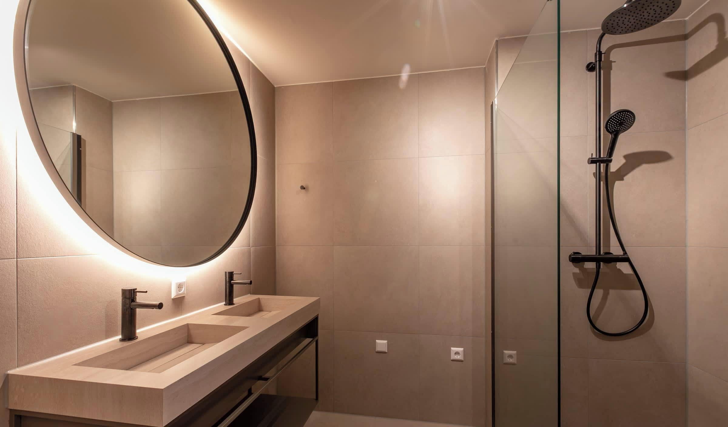 A modern bathroom with a double sink, a large mirror, and a glass-enclosed shower area.