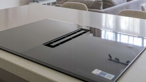 A modern kitchen with a stainless steel range hood, a flat-screen TV, and a dining table with chairs. - Modern 3BR Apartment in Rotterdam Centre (Rotterdam)