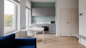 Uma cozinha moderna com armários brancos, uma mesa de jantar e um sofá azul.
