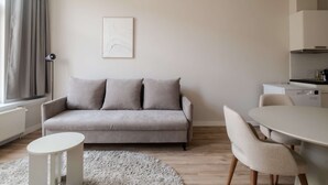 Una sala de estar moderna con un sofá gris, una mesa redonda blanca y un comedor con sillas.