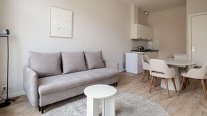 Una sala de estar moderna con un sofá gris, una mesita blanca y un comedor con sillas.