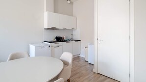 Una cocina moderna con gabinetes blancos, una encimera negra y un lavavajillas blanco.