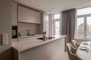 Une cuisine moderne dotée d’un îlot central, d’appareils électroménagers intégrés et d’un coin repas avec une table et des chaises.