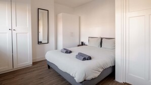 Ein Schlafzimmer mit Bett, Kleiderschrank, Spiegel und Nachttisch.