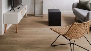 A modern living room with a flat-screen TV, a large mirror, a black ottoman, a wicker chair, and a grey sofa. - Cosy City Apartment in Rotterdam West (Rotterdam)