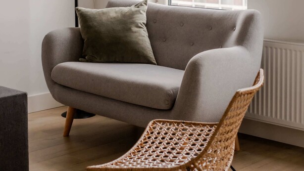 A modern living room with a sofa, a wicker chair, and a floor lamp. - Cosy City Apartment in Rotterdam West (Rotterdam)