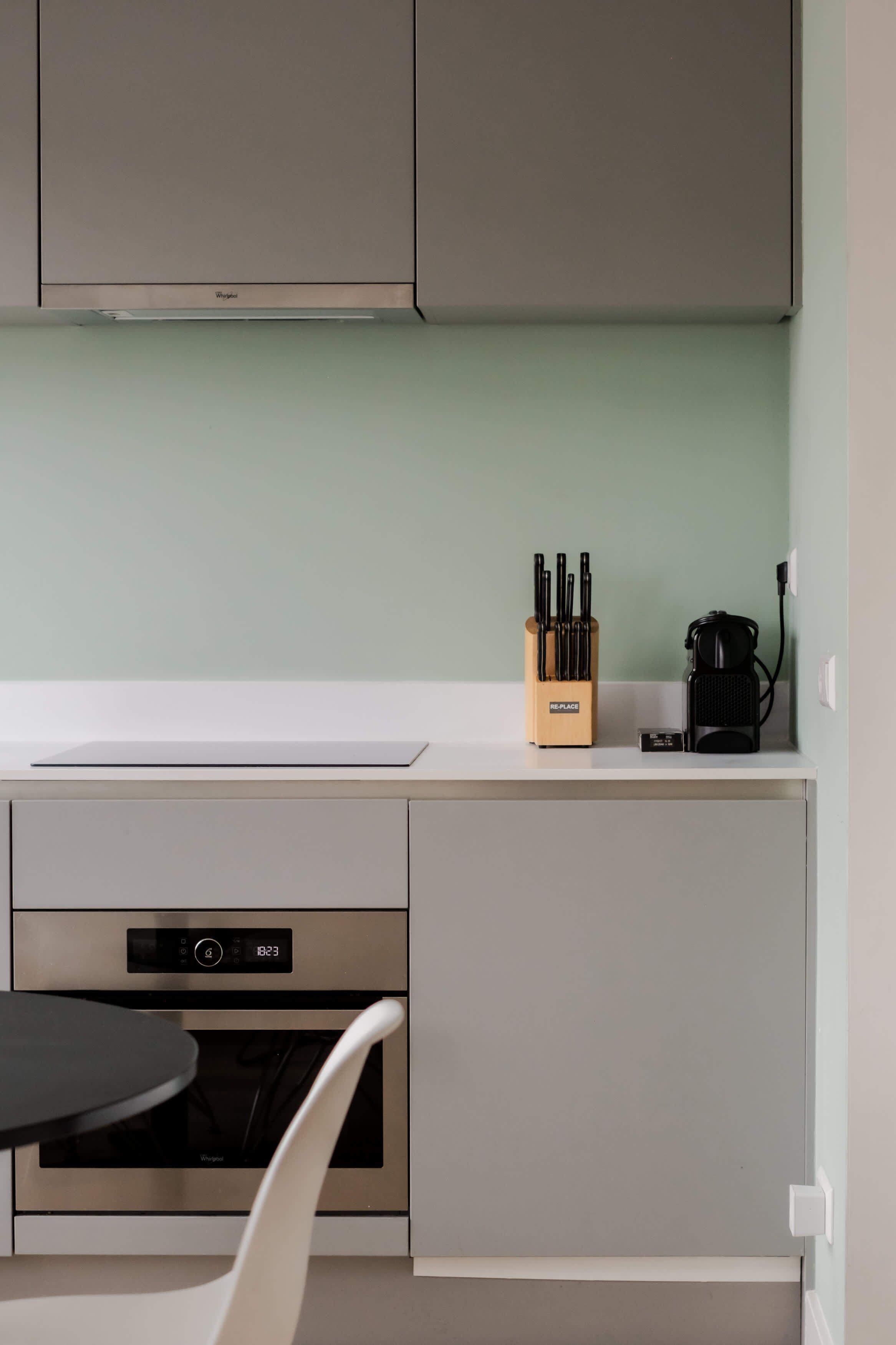 A kitchen with a built-in oven, a coffee machine, and a knife block on the counter.