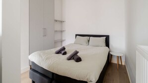 A bedroom with a bed, a wardrobe, a small table, and a radiator. - Cosy City Apartment in Rotterdam West (Rotterdam)