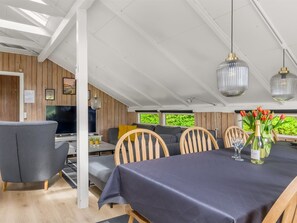 Ein Essbereich mit einem Tisch für vier Personen, Holzsesseln und einem Fernseher im Hintergrund.