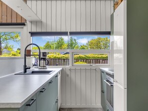 Eine moderne Küche mit Einbauofen, einer Kaffeemaschine und einem Fenster mit Blick auf einen Garten.