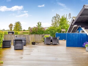 Eine Holzterrasse mit Gartenmöbeln, einem blauen Zaun und einer Satellitenschüssel.