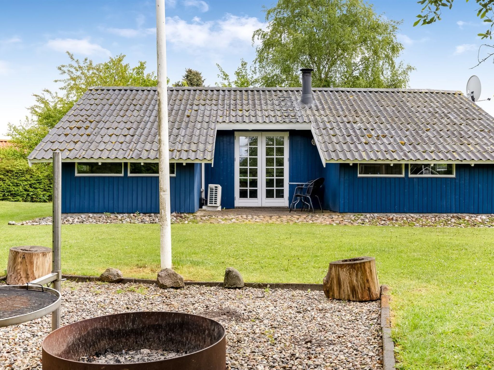 A blue building with a tiled roof, a door, and windows.