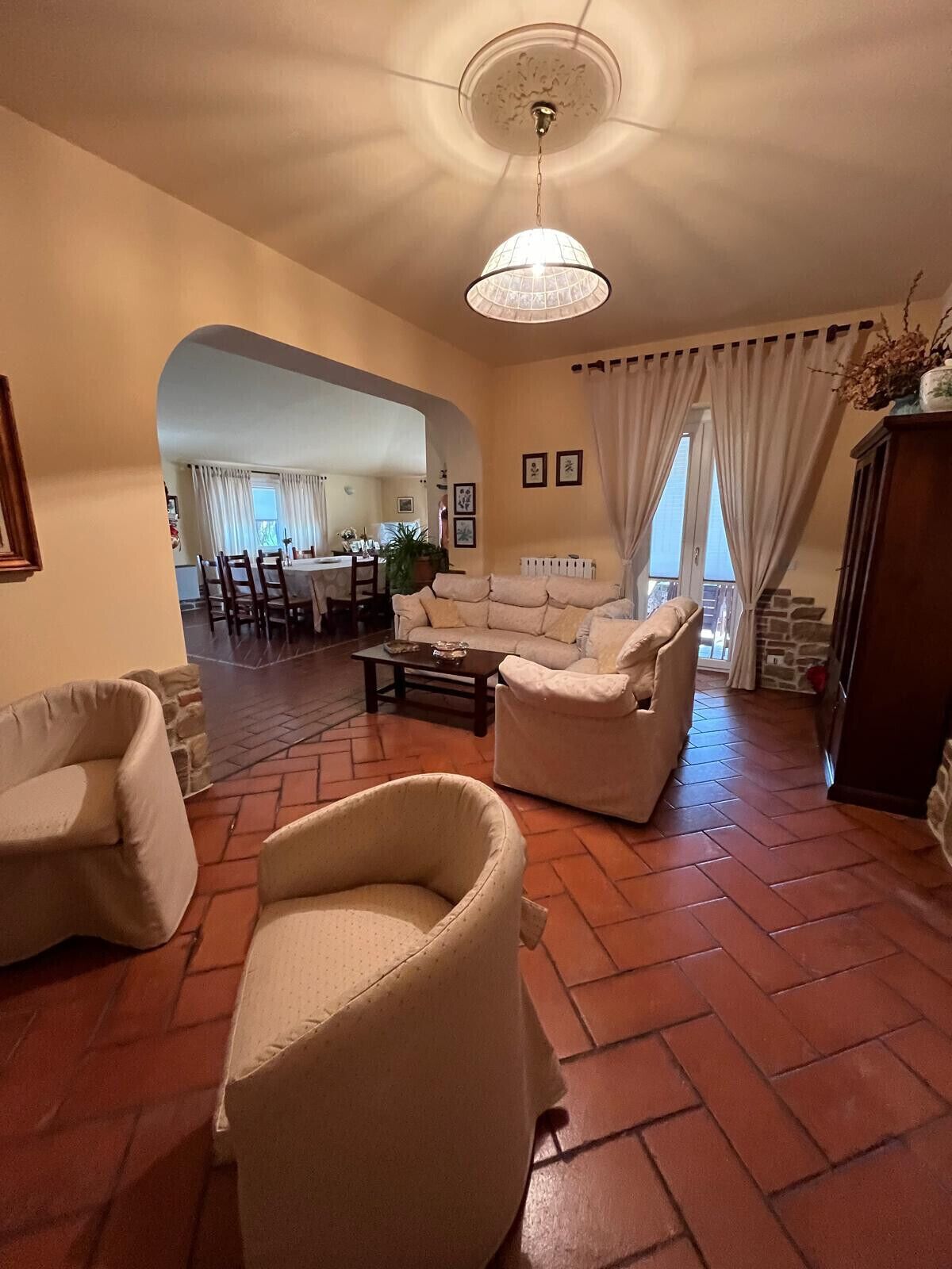 A living room with a sofa, armchairs, a coffee table, and a dining area in the background.