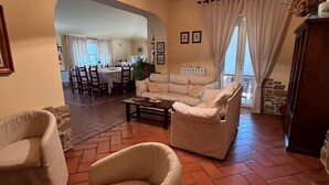 A living room with a sofa, armchairs, a coffee table, and a dining area in the background. - Farmhouse - Villa Montesegnale (Bolsena)