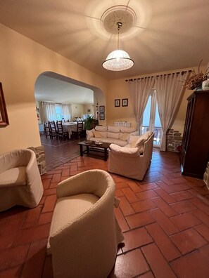 A living room with a sofa, armchairs, a coffee table, and a dining area in the background. - Farmhouse - Villa Montesegnale (Bolsena)