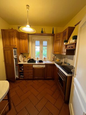 A compact kitchen with wooden cabinets, a built-in dishwasher, and a stove. - Farmhouse - Villa Montesegnale (Bolsena)