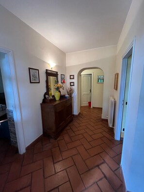 A hallway with a herringbone floor pattern, a wooden cabinet with a mirror, and framed pictures on the walls. - Farmhouse - Villa Montesegnale (Bolsena)
