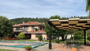 A two-story house with a balcony, a covered patio area with outdoor furniture, and a swimming pool. - Farmhouse - Villa Montesegnale (Bolsena)