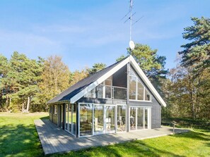 Ein modernes Haus mit einer großen Glasfassade, einem geneigten Dach und einer Satellitenschüssel.