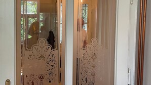 Una porta blanca amb panells de vidre gravat decoratiu i un tirador de bronze.