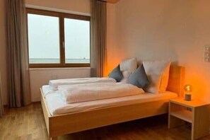 Ein Schlafzimmer mit einem Bett, einem Nachttisch, einem Fenster und Blick zum Himmel.