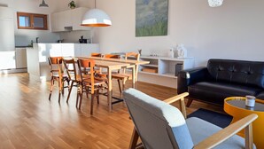 A modern living space with a dining area, kitchen, and seating area.