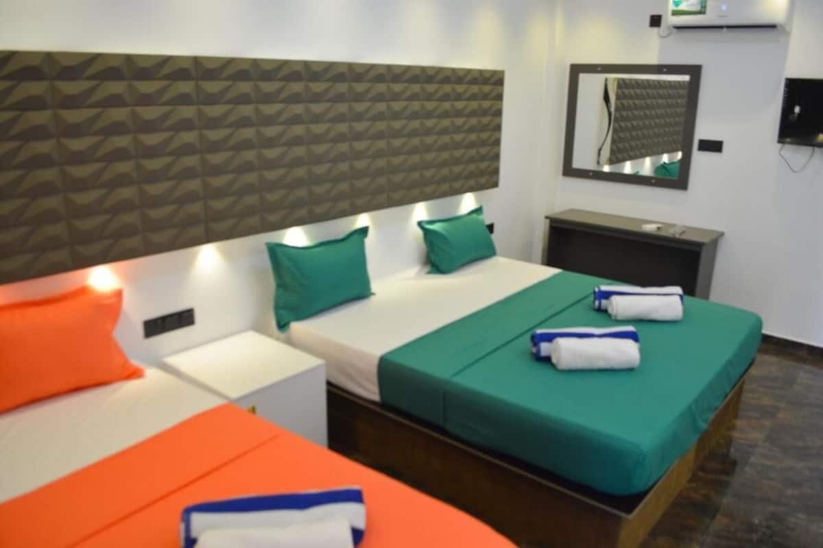 Habitación de hotel con cama, mesita de noche, espejo y aire acondicionado de pared.