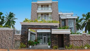 A modern two-story building with a stone facade, a balcony, and a gated entrance.