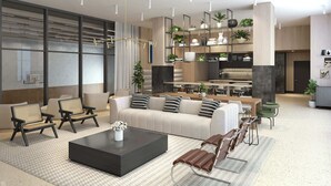 Ein modernes Wohnzimmer mit einer Couch, einem Couchtisch und Sesseln. Es gibt eine Küchenzeile mit einem Esstisch und Stühlen.