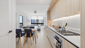 A modern kitchen with a built-in oven, a sink, and a dining area with a table and chairs. - District 225 Downtown Miami (Miami)