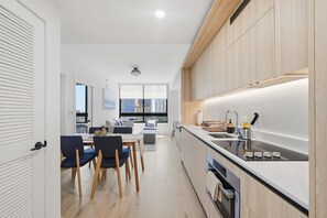 A modern kitchen with a built-in oven, a sink, and a dining area with a table and chairs.
