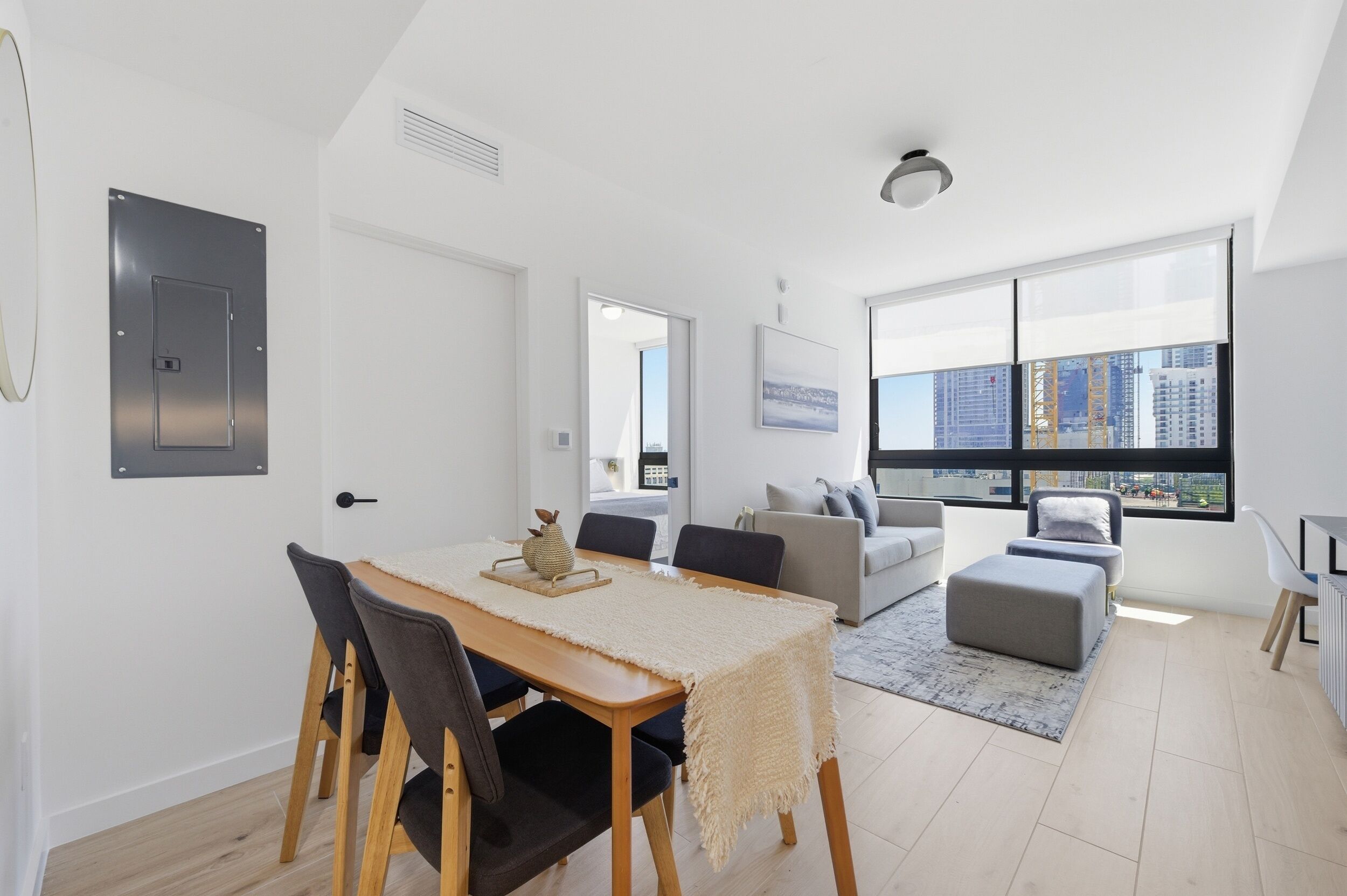 A modern living room with a dining area, large windows, and a city view.