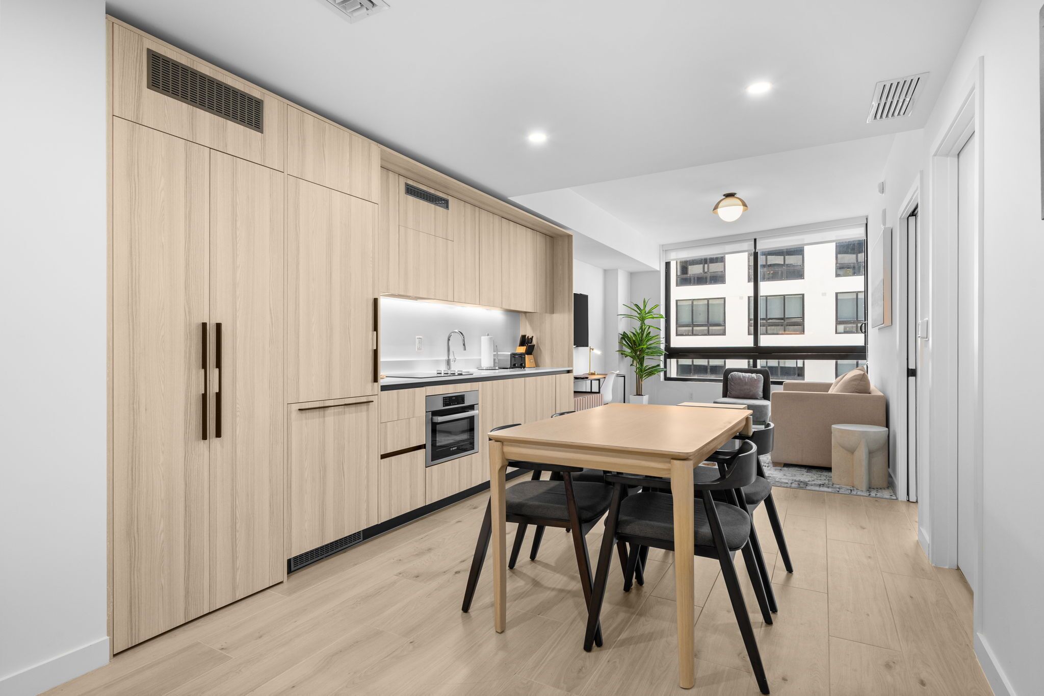 A modern kitchen with wooden cabinets, a dining table, and chairs.