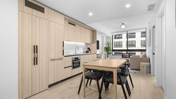 A modern kitchen with wooden cabinets, a dining table, and chairs.