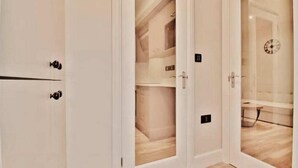 Una camera d'albergo con porte bianche, pavimento in legno e un orologio appeso al muro.