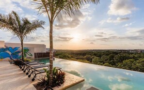 Ein Pool im Endlos-Design mit Blick auf die Landschaft, eine Palme und ein Wandgemälde.