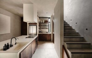 Eine moderne Küche mit einer großen Kochinsel, eingebauten Schränken und einer Treppe zu einer weiteren Ebene.