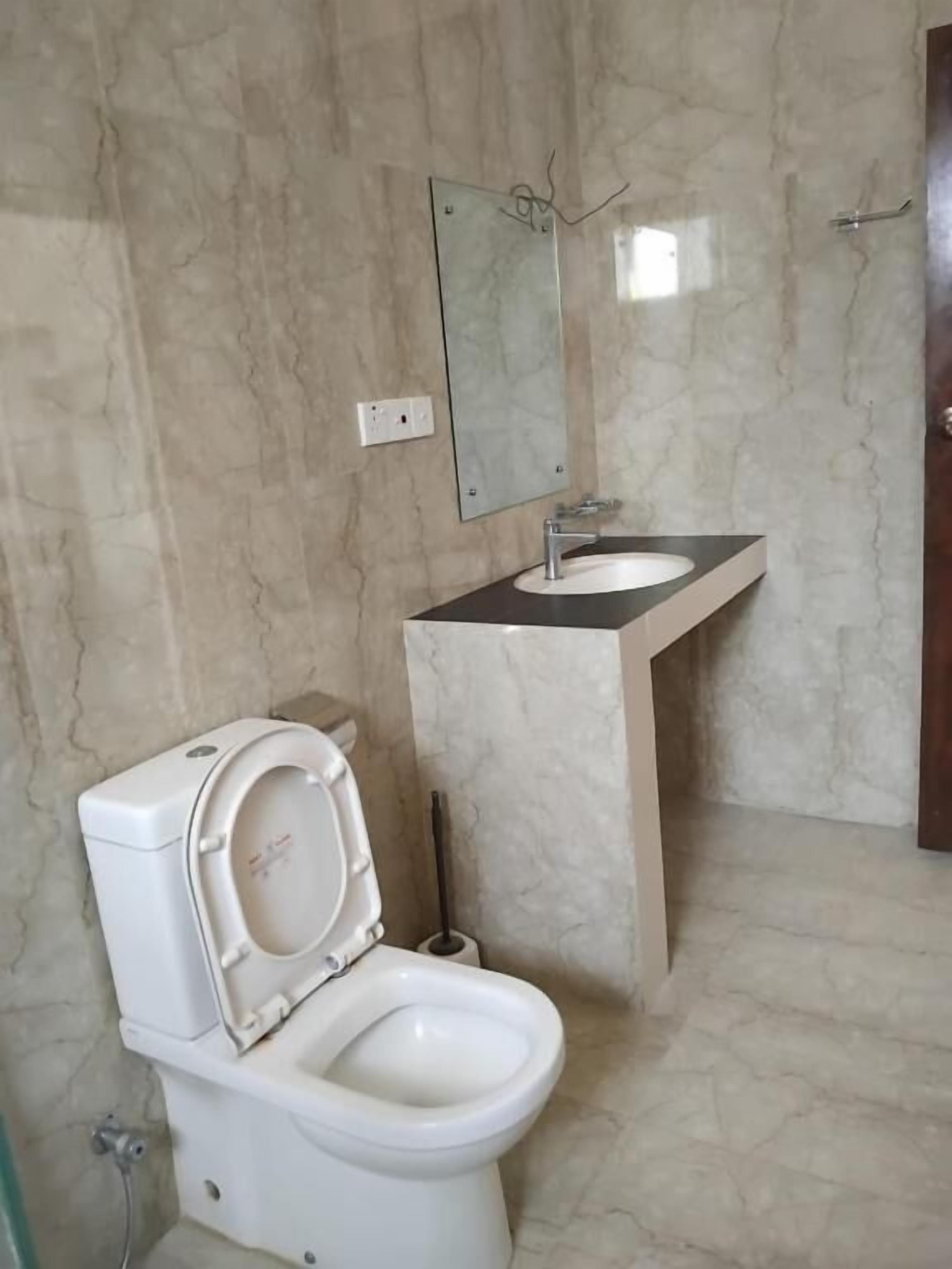 Un baño con inodoro, lavamanos y espejo.