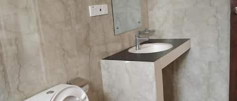 Un baño con inodoro, lavamanos y espejo.